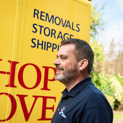 Bishop’s Move employee smiling in front of a branded yellow moving van.