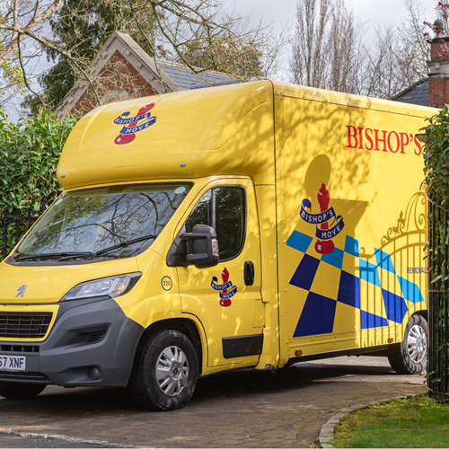 A yellow Bishop's Move van pulling into the driveway of a home