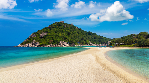 Stretch of sand on a beach leading to a forested peak on Koh Tao, Thailand.