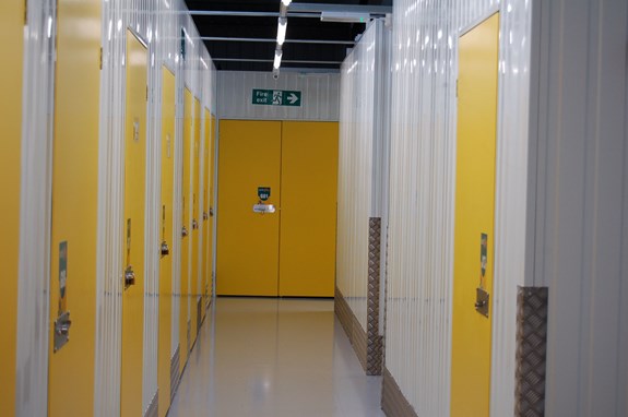 Self-storage units with yellow doors in a corridor.