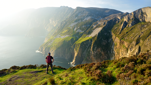 an standing looking out at dramatic cliffs of Ireland