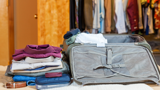 Suitcase and clothes in front of an open wardrobe