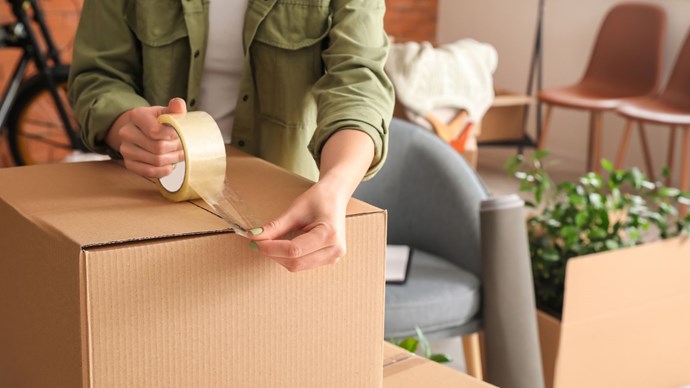 A woman packing a moving box at home.