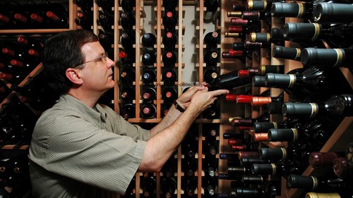 A wine enthusiast selecting a bottle from his personal collection.