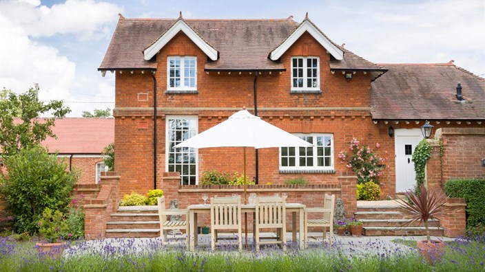 A large luxury detached house in the UK with garden furniture on the patio.