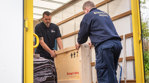 Two removals professionals handling a wooden box