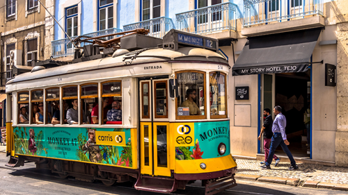 Colourful tram driving through Lisbon on a sunny day