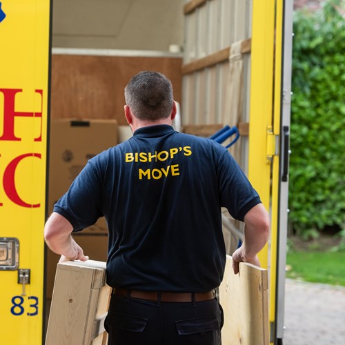 Bishop's Move employee carrying flat pack crates into a moving van