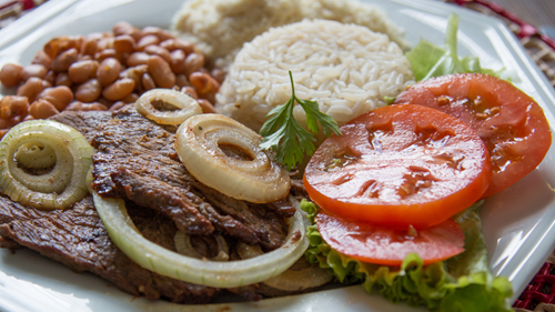 A typical Brazilian dish of beef and onions served with beans, rice and salad.