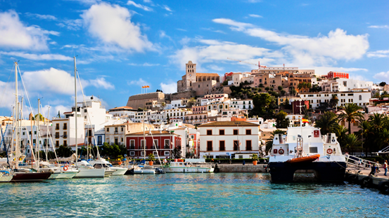 A view of the port in Ibiza with sailing boats and buildings overlooking