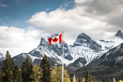 Canadian flag on a pole near a snow-covered mountain