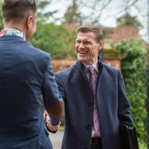 2 men in suits shaking hands and greeting each other